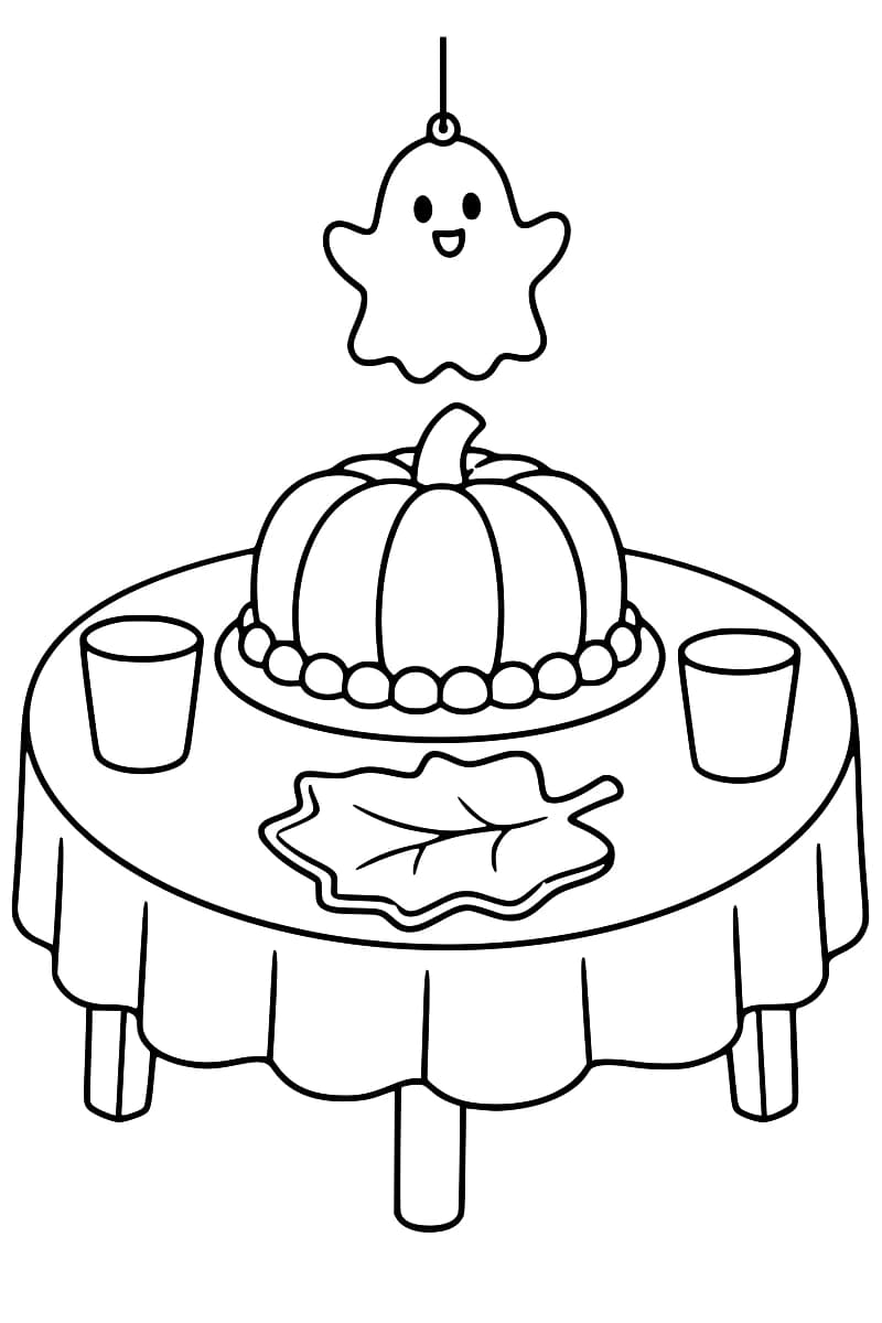 Table d’Halloween avec un gâteau citrouille et une décoration fantôme.